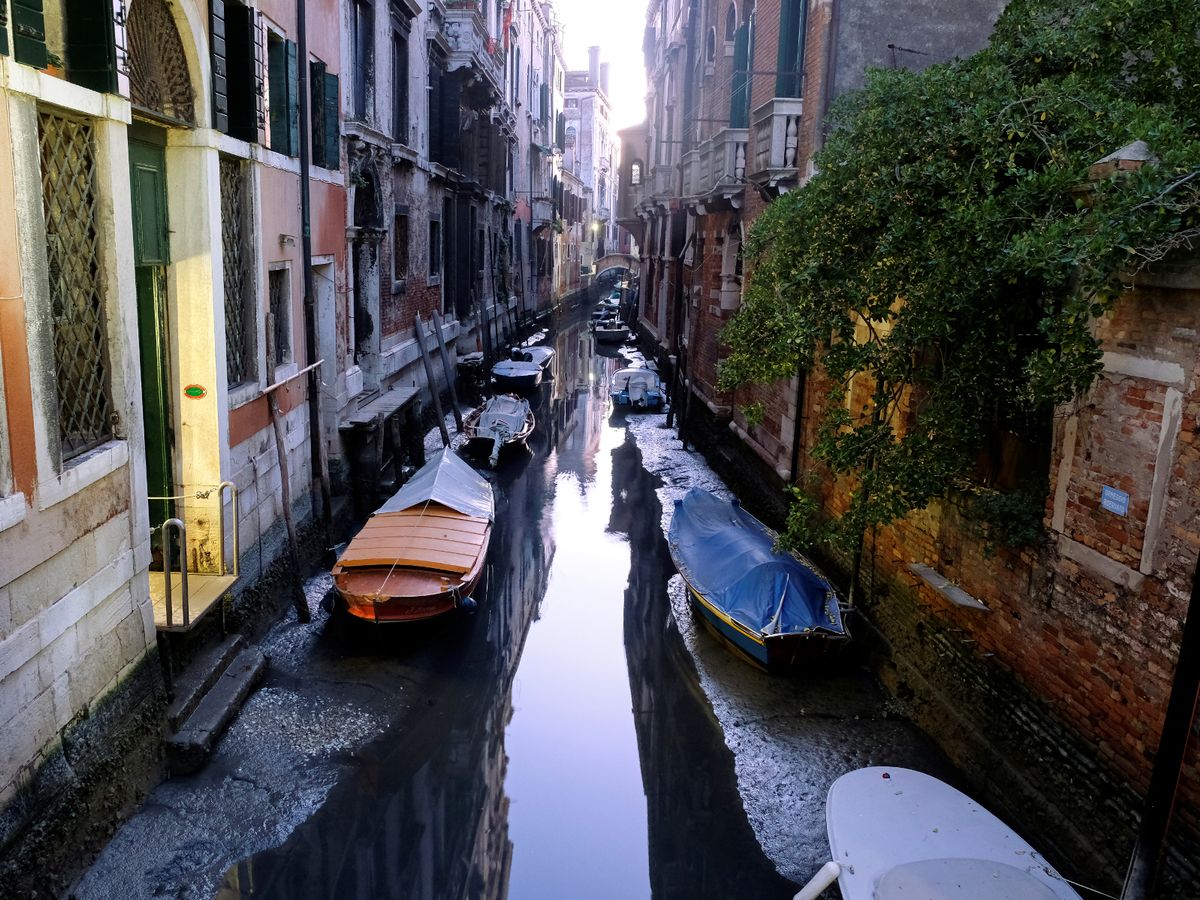 - 0 General view of a canal with boats during an exceptional low tide in the lagoon city of Venice - ອິຕາລີປະເຊີນໄພແຫ້ງແລ້ງຮອບໃໝ່ ເຮັດໃຫ້ຄອງນ້ຳເມືອງເວນິສແຫ້ງ ເຮືອບໍ່ສາມາດໄປ-ມາໄດ້